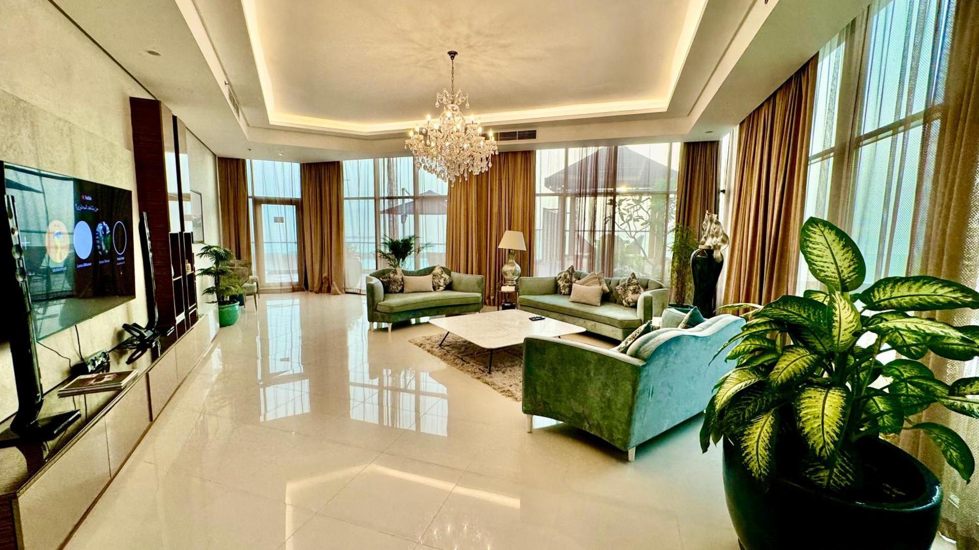Lagoona Beach Luxury Resort And Spa Manama Eksteriør billede The photo depicts a spacious and elegantly designed living room. The room features large windows allowing natural light to flood in, accompanied by sumptuous curtains. The furniture includes a pair of soft green sofas and a centerpiece coffee table s
