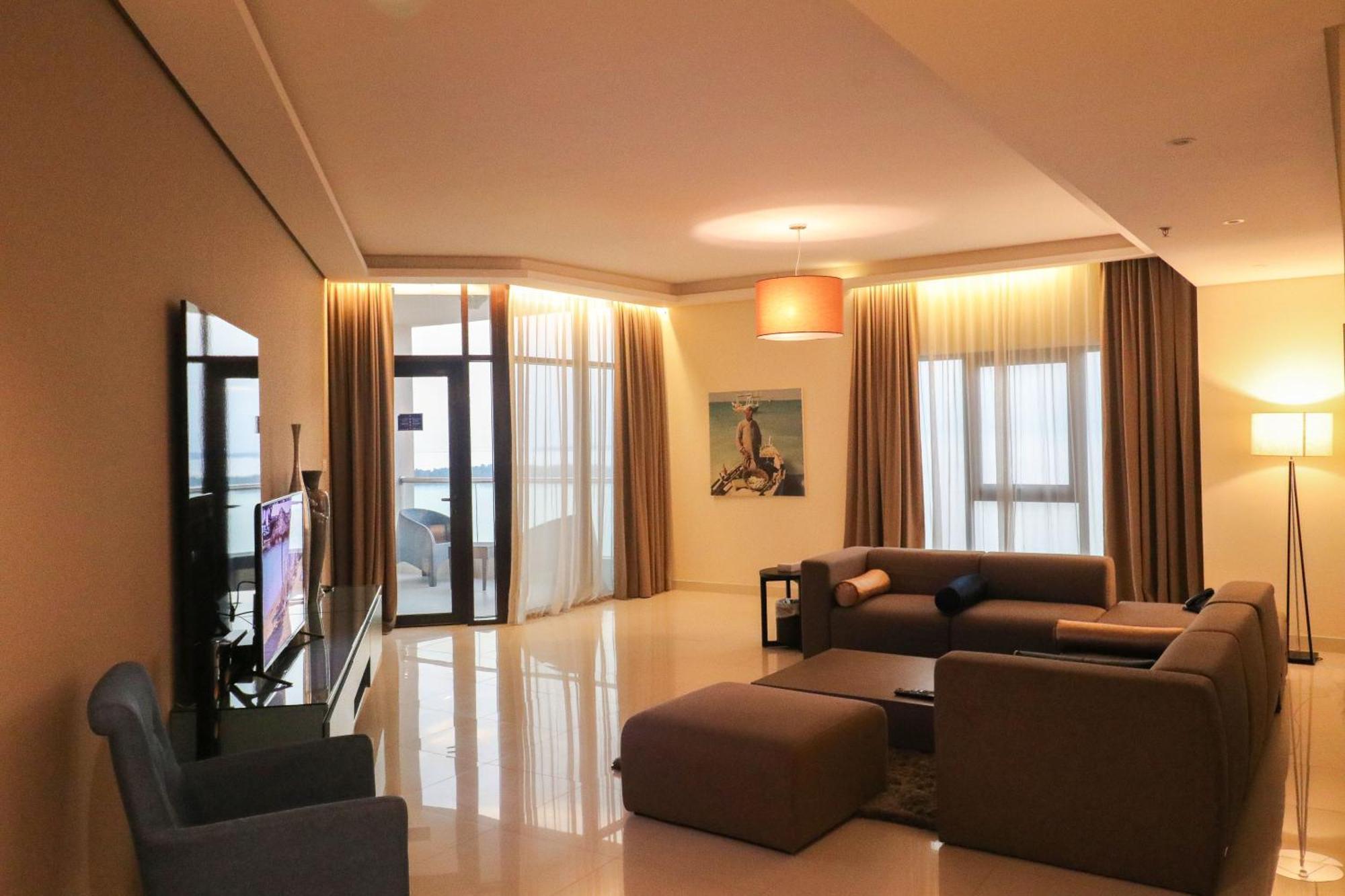 Lagoona Beach Luxury Resort And Spa Manama Eksteriør billede The photo shows a modern living room with a spacious and elegant design. It features a large couch in neutral tones, a soft ottoman, and a stylish coffee table. The walls are painted in a light color, and there are large windows with sheer curtains a